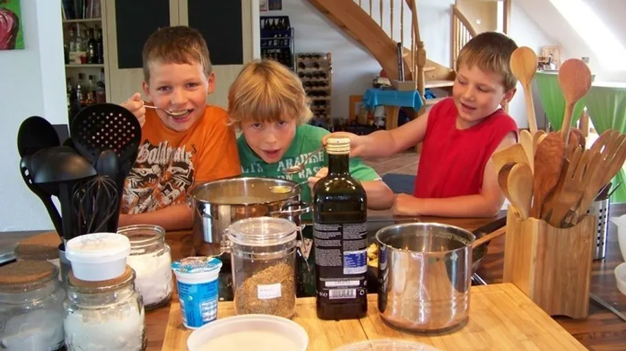 Three boys cooking in a kitchen together.