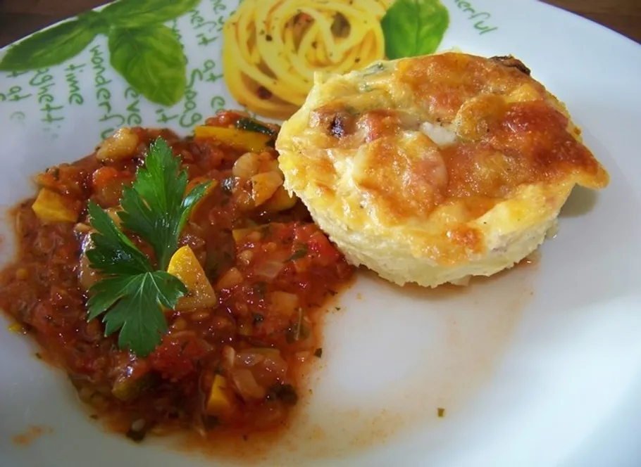 Quiche with tomato sauce on decorative plate.