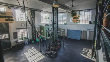 Fitnessstudio mit Trainingsgeräten und Seilen.