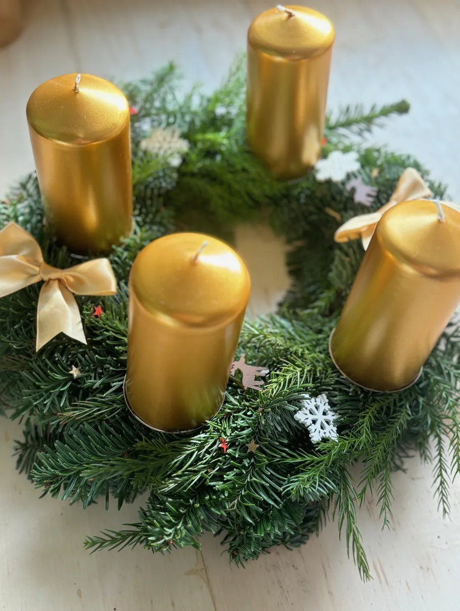 Golden candles on greenery wreath, festive decor.