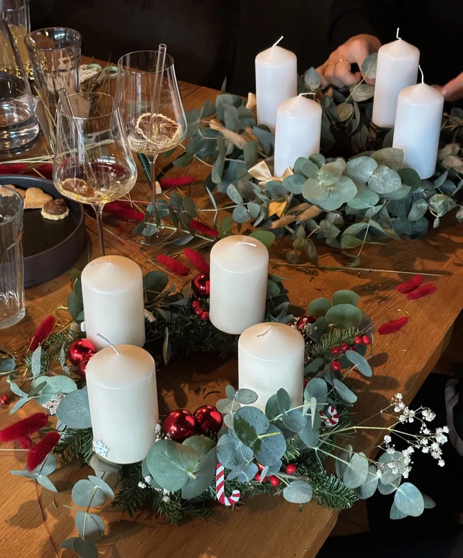 Decorative candle wreaths on wooden table.