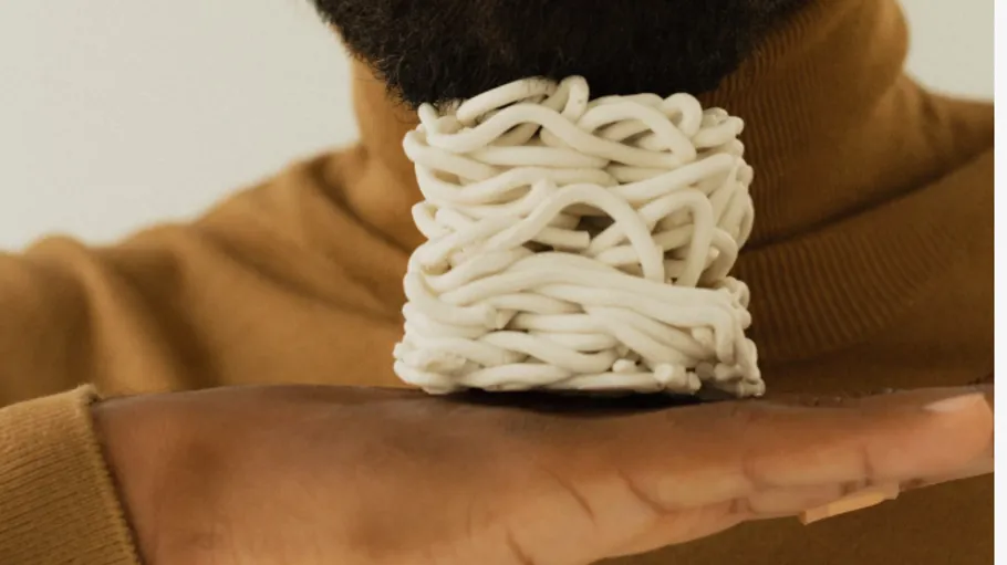 Hand with woven ceramic piece near beard.