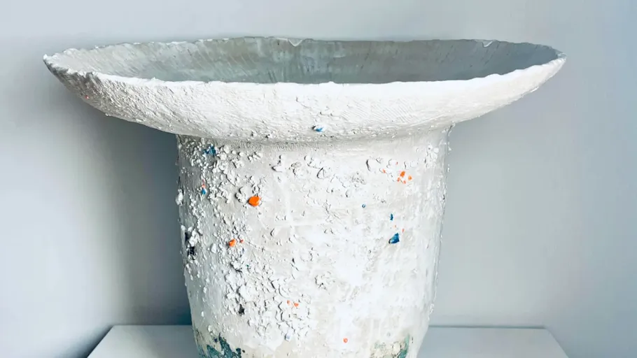 Weiße strukturierte Vase auf flacher Fläche.