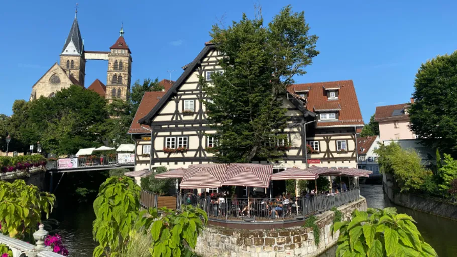 Half-timbered house by a river with church.