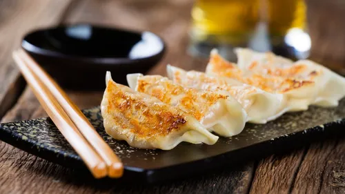 Four dumplings on a black plate, wooden table.