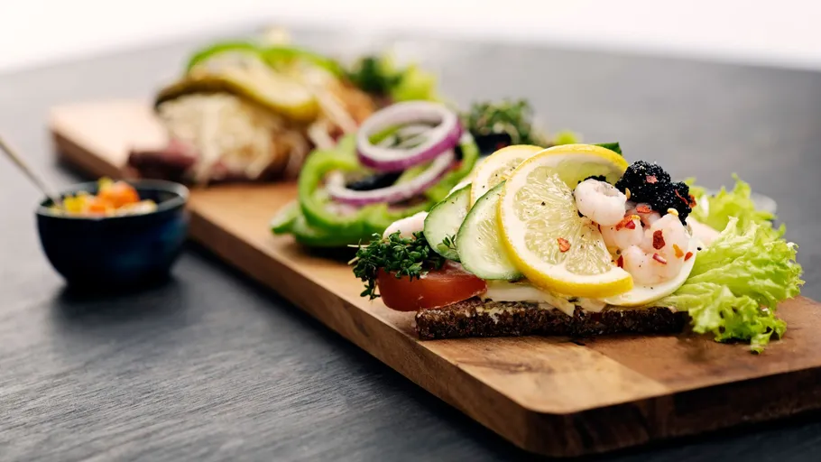 Open sandwiches with toppings on wooden board.