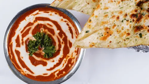 Butter chicken with naan on plate.