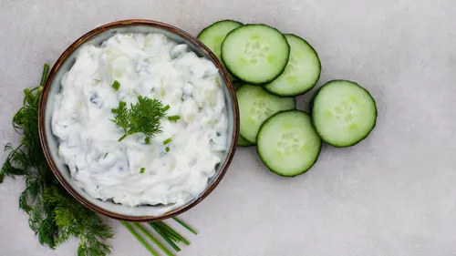 Bowl of tzatziki with cucumber slices.