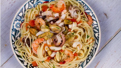 Seafood pasta with shrimp and shellfish on plate.