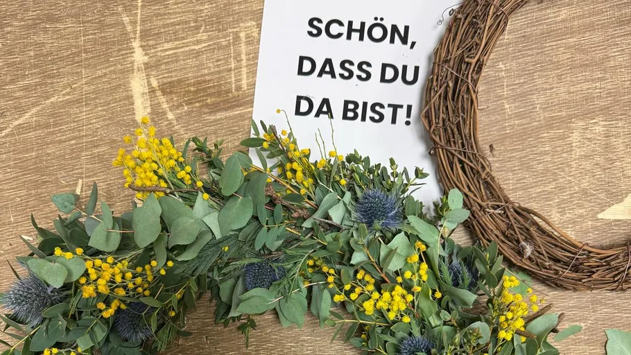 Blumenkranz neben einem Willkommensschild.