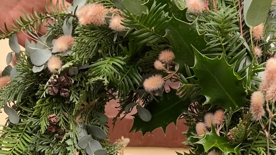 Grüner Kranz mit Zapfen und rosa Flusen.