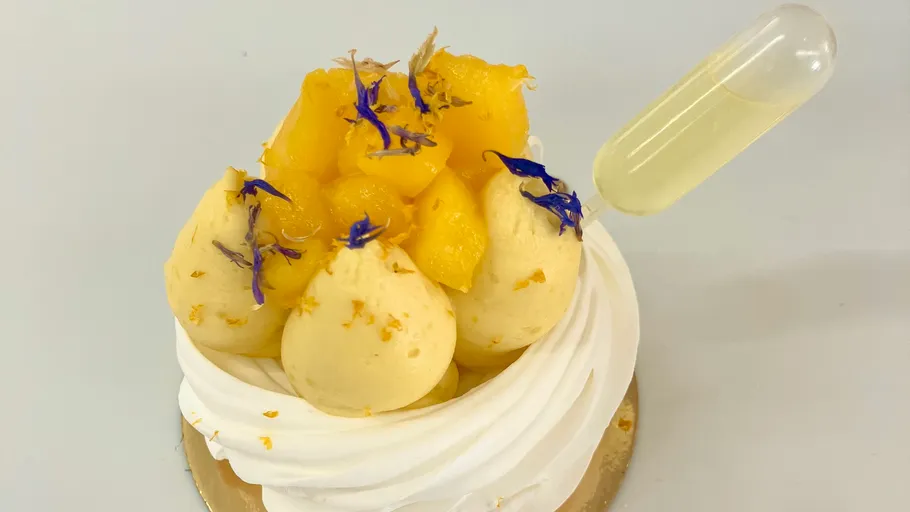 Pavlova mit Sahne, Mango und Pipettengarnitur.