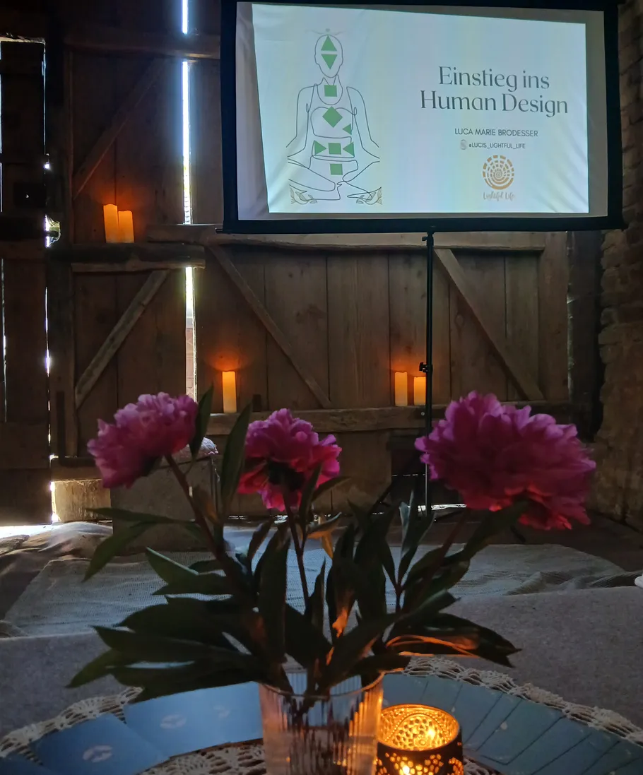 Bildschirm mit Human-Design-Präsentation, gedämpftes Kerzenlicht.
