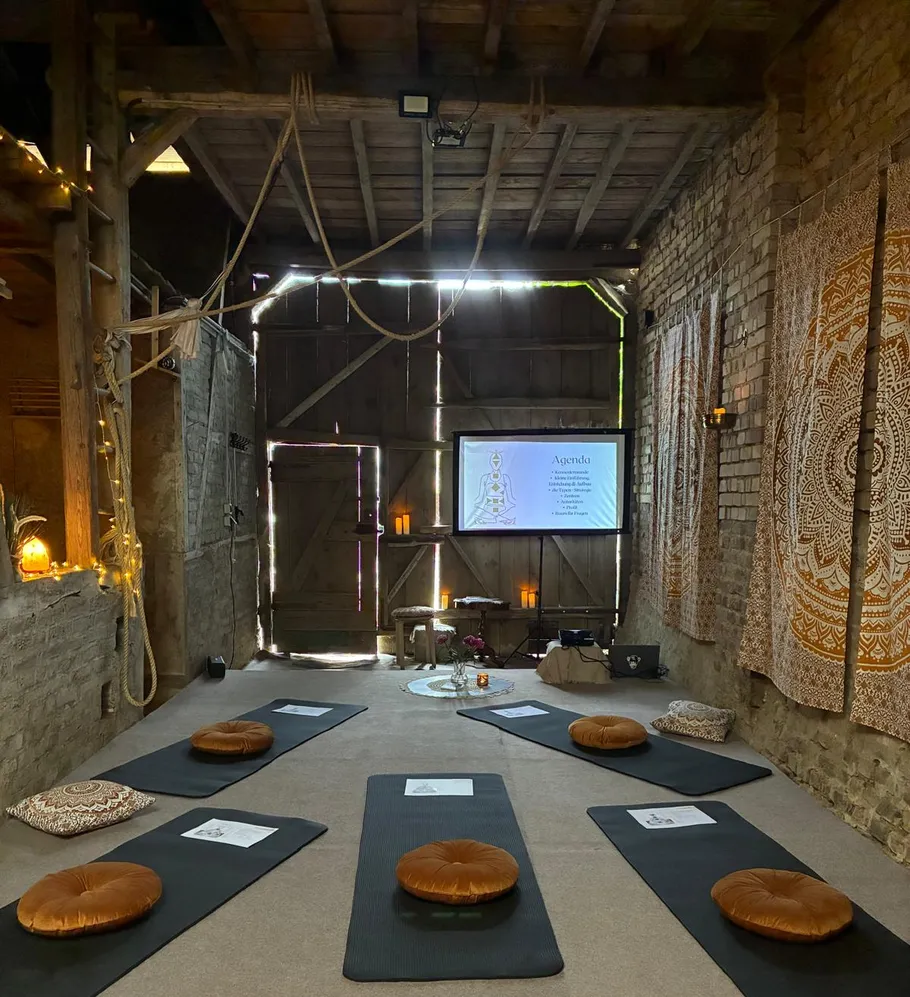 Meditationsraum mit Matten und Projektionsleinwand.
