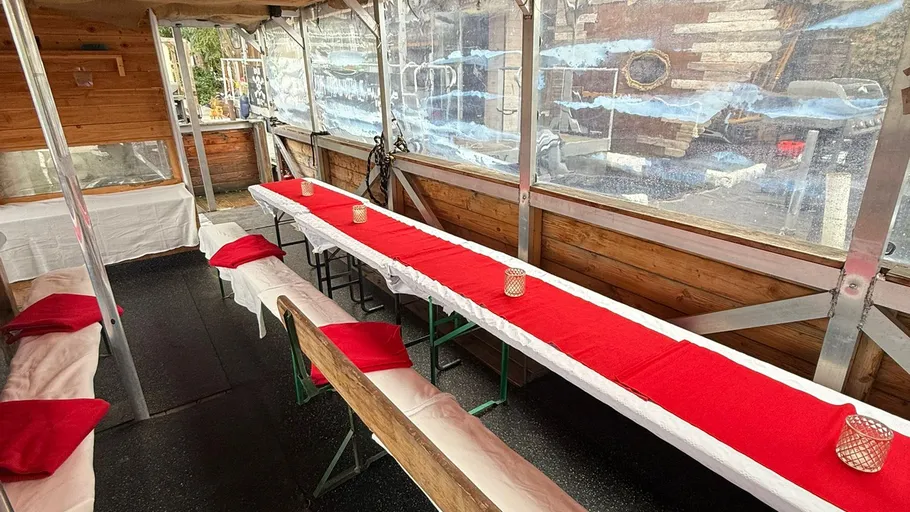 Langer Tisch mit rotem Tuch im Außenzelt.