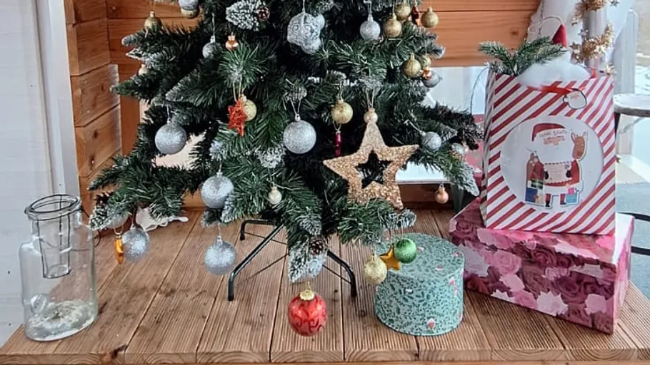 Weihnachtsbaum mit Geschenken in einem Holzraum.