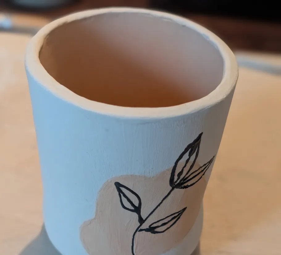Handgefertigte Tasse mit Blattdesign, auf Tisch.