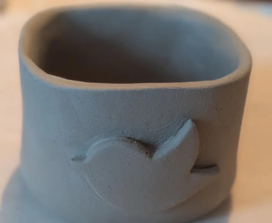 Tonk Becher mit Vogelmotiv, auf Tisch.