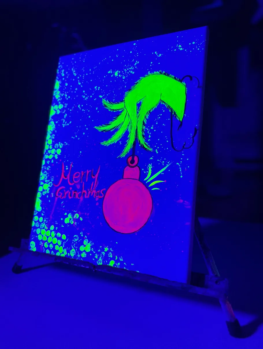 Canvas with neon Grinch hand under UV light.