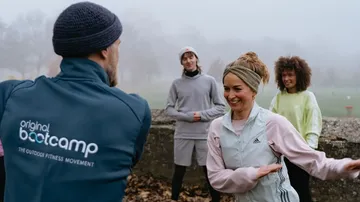 Group exercising outdoors in foggy park.