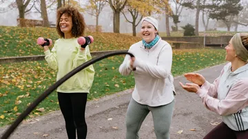 Three women exercising outdoors in a park.