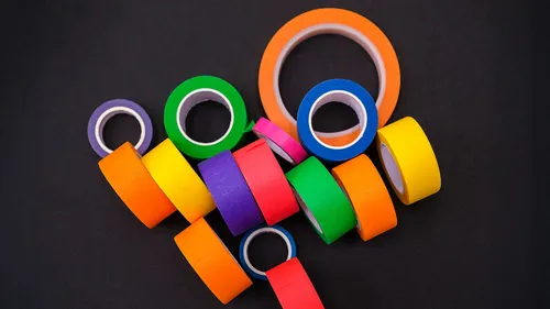 Bunte Klebebandrollen auf schwarzem Hintergrund.