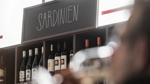 Weinflaschen unter 'SARDINIEN' Schild ausgestellt.