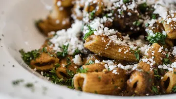 Pasta with cheese and herbs in bowl.