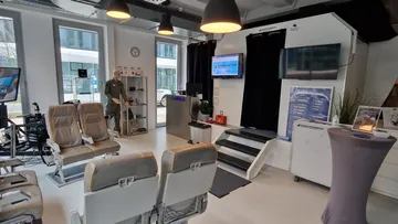 Büro mit Flugzeugsitzen, Bildschirmen und Schaufensterpuppe.