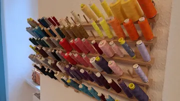 Colorful thread spools on a wooden rack.