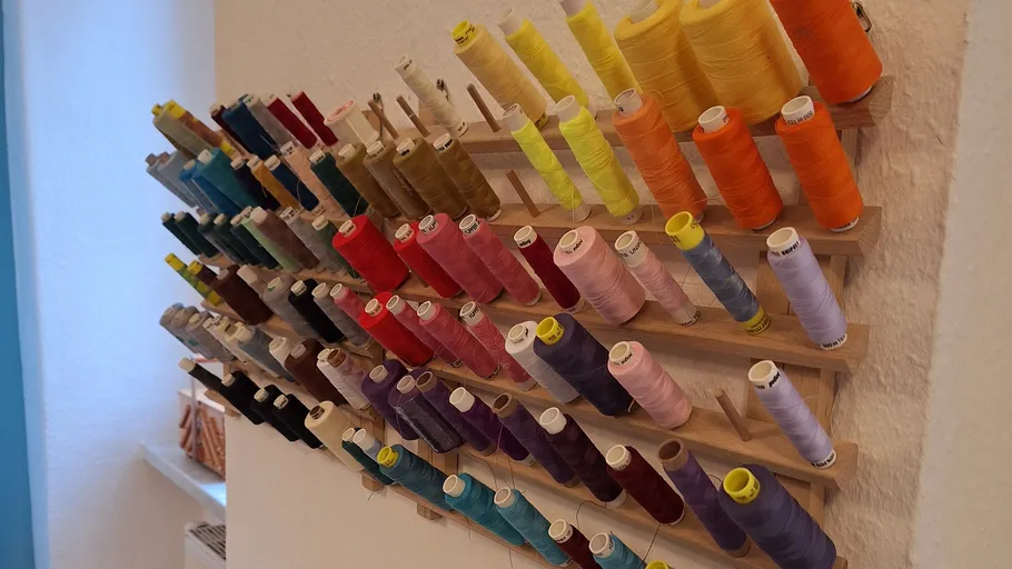Colorful thread spools on a wooden rack.