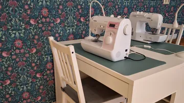 Nähmaschinen auf weißem Tisch in Blumenraum.