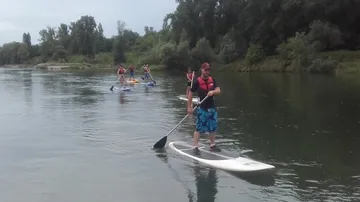 People paddleboarding on a calm river.