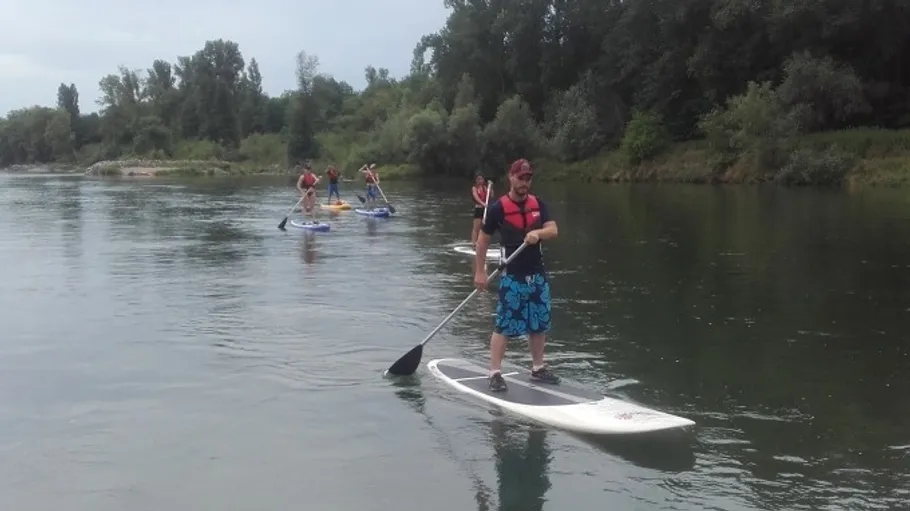 Personen beim Paddeln auf einem ruhigen Fluss.