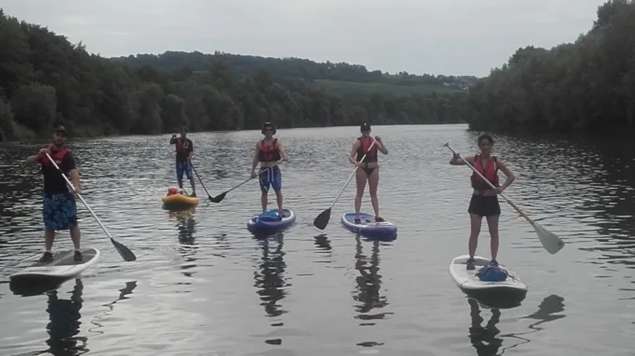 Fünf Personen beim Stand-up-Paddeln auf einem Fluss.