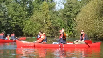 People in red canoes on a river.