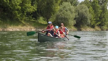Familie paddelt im Kanu auf einem Fluss.