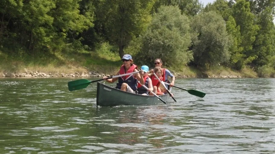 Familie paddelt im Kanu auf einem Fluss.