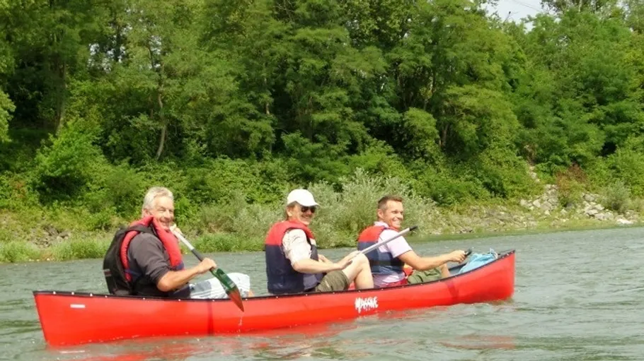 Three people canoeing on a river.