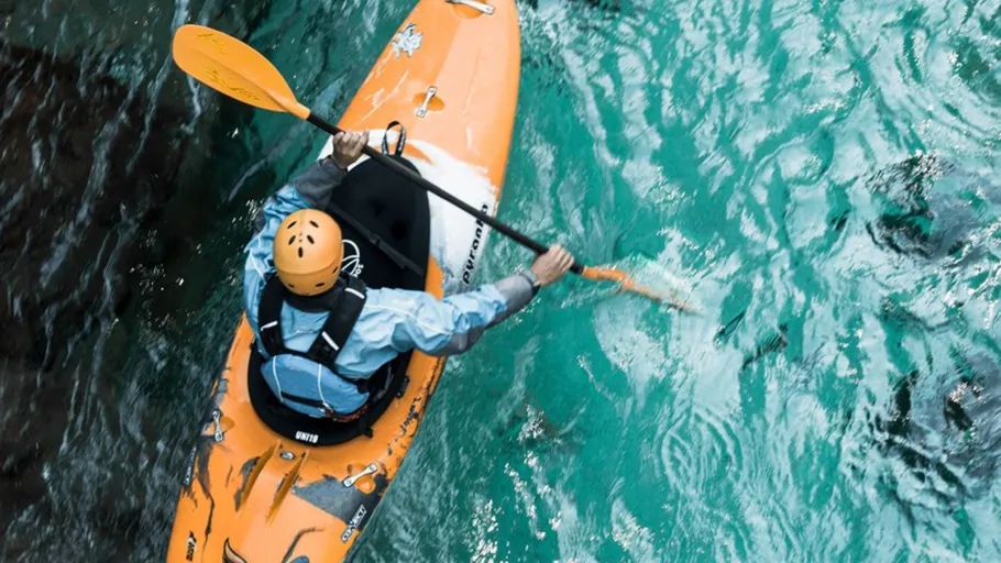 Person kayaking on clear turquoise water.