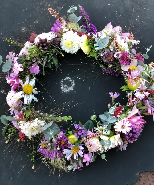 Wreath of colorful flowers on dark surface.