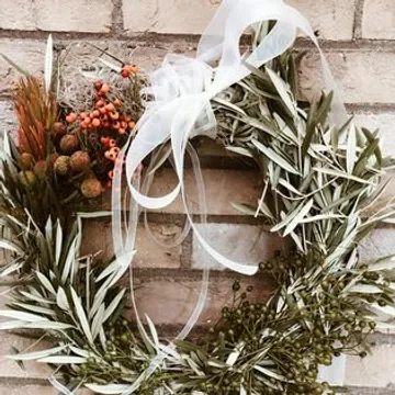 Floral wreath with ribbon on brick wall.