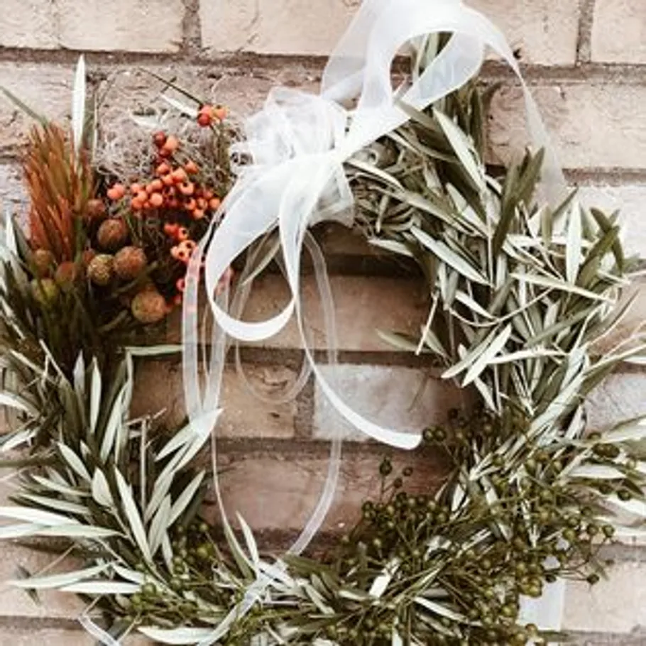 Floral wreath with ribbon on brick wall.