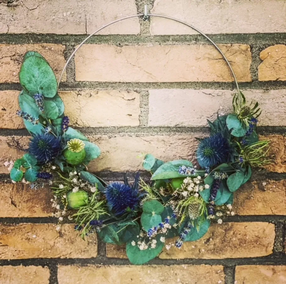 Floral wreath hangs on rustic brick wall.