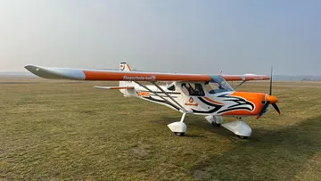 Small orange airplane on grassy airfield.