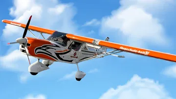 Orange airplane flying in blue sky.