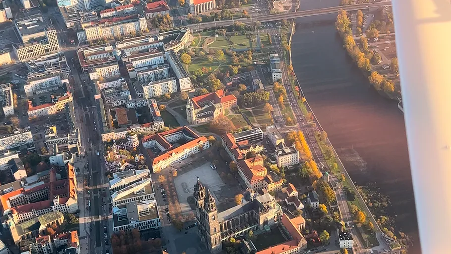 Aerial view of river, buildings, and green park.