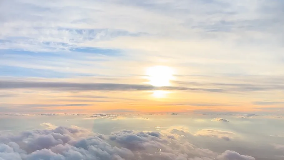 Sun setting over clouds, colorful sky.
