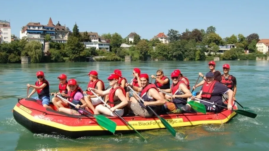 Gruppe rafting auf einem Fluss nahe einer Stadt.
