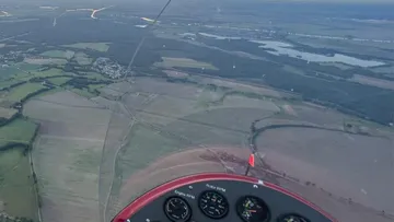 Aerial view from aircraft cockpit over fields.